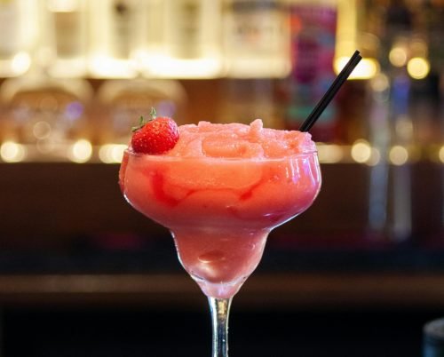 A vibrant strawberry margarita cocktail in a glass with a straw, perfect for a summer evening.